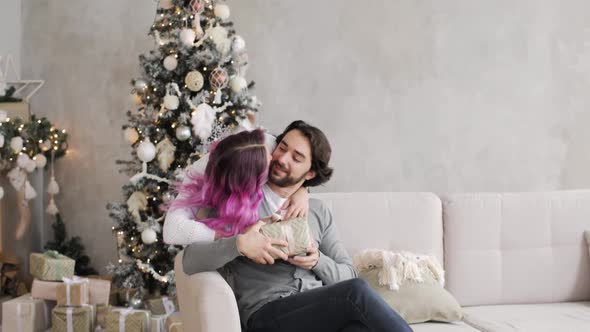 Young Woman Gives a Gift To Her Husband in New Year's Interior at Home.