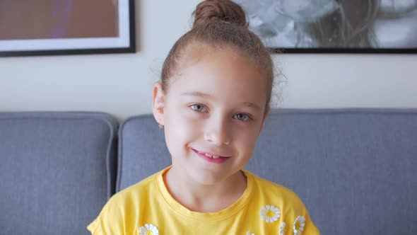 Portrait Funny Little Girl Smiling Child Looking at Camera Are Sitting on the Couch at Home, Cute