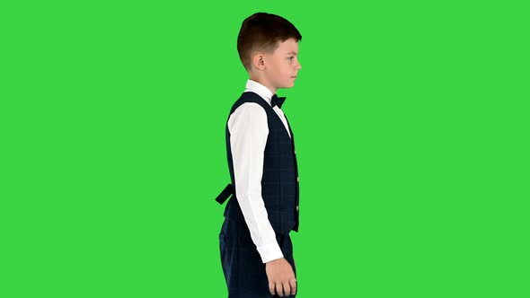 Little Boy in a Waistcoat and a Bow Tie Walking Looking Straight Ahead on a Green Screen Chroma Key