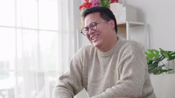 Man laughing and sitting on sofa and  spending time to watch comedy series at home