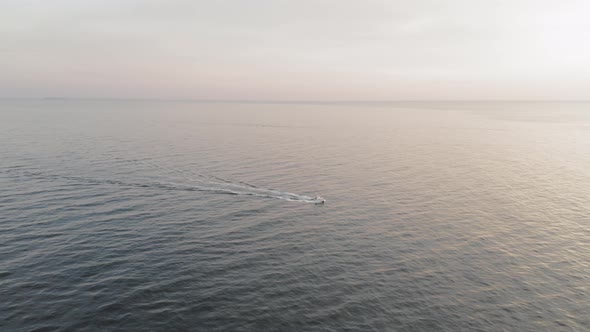 Tilting down on a boat motoring across the sea during a winter sunrise off the coast of Maine AERIAL