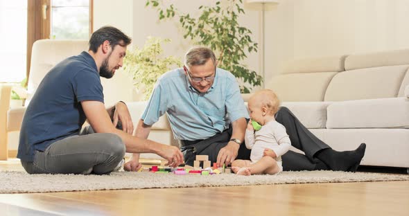 A Father with Son and Grandson Spend Family Time Together Stacking Blocks on the Carpet
