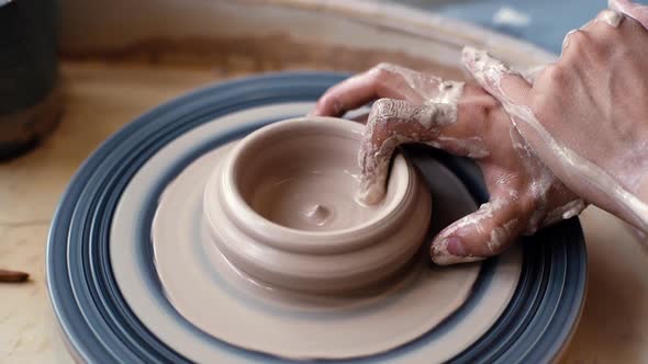 Closeup Hands of Unrecognizable Potter Making Ceramic Cup with Dirty Arms on Twisted Pottery Wheel