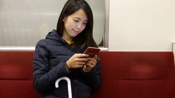 Woman using cellphone inside train compartment