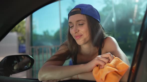 Portrait of Positive Professional Woman Posing in Sunrays at Car Wash Service