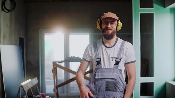 Worker in Safety Headphones and Glasses Stands in Studio Showing Thumb Up