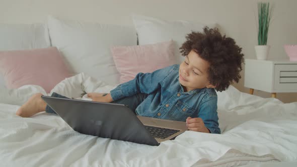 Mixed Race Boy Enjoying Movie Online on Laptop alt