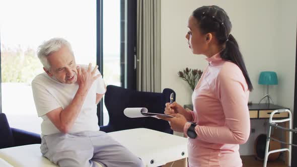 Video of biracial female physiotherapist examining caucasian senior man