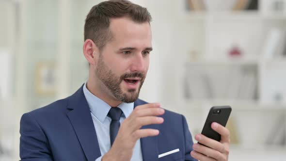 Portrait of Excited Businessman Celebrating on Smartphone 