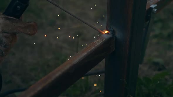 Slow Motion Closeup Handyman Welds Fence Part to Support