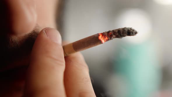 Male portrait,close up: man smokes a cigarette in a workshop. The sculptor is tired and resting.