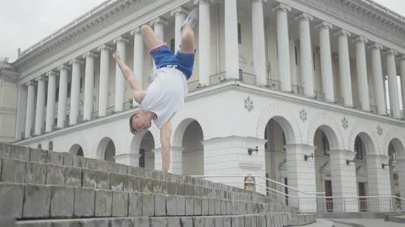 Wide Shot of Confident Break Dancer Moving Legs Up As Standing on One Hand. Portrait of Athletic