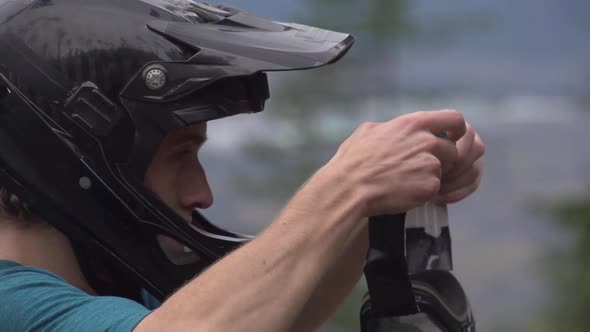 A young man mountain biker putting on goggles.