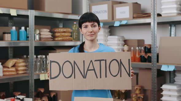 Woman Holding Banner with Word Donation at Warehouse