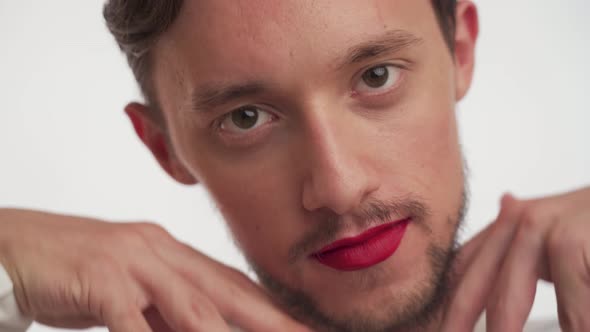 Caucasian brunette man with beard painted lips show off his face, stare camera on white background