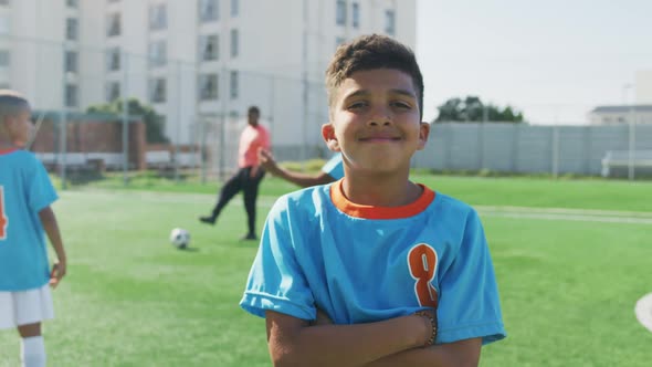 Mixed race soccer kid in blue smiling and looking at camera