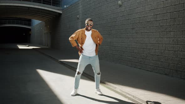 Joyful AfroAmerican Guy Dancing and Having Fun Outdoors with Modern Building in Background