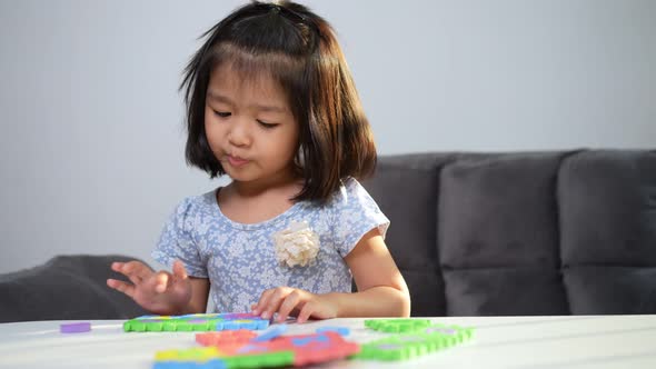 Cute Asian little girl playing with colorful toy ABC jigsaw, Kids play with educational toys at kind