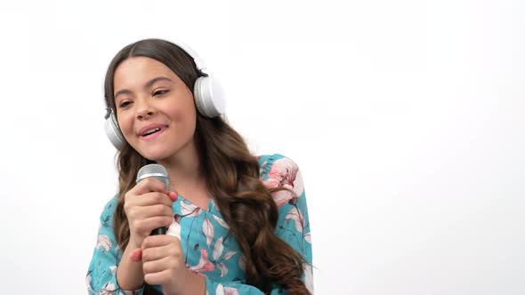 Talented Happy Teen Girl Singer Listen Music in Headphones and Sing Karaoke in Microphone Singing