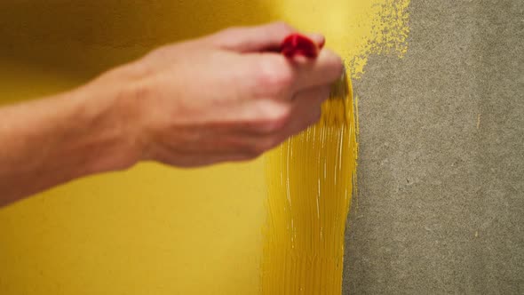 Painting Walls with Yellow Paint Using Brush Closeup