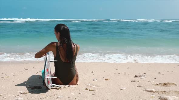 Surf in Ocean. Beautiful Surfer Woman with Long Hair with Surfboard or Longboard Sitting on the Sea