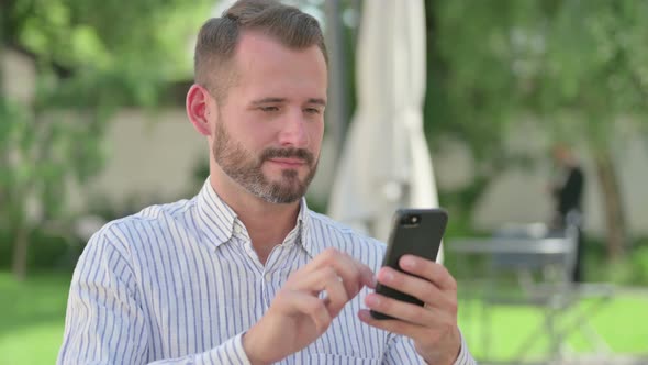 Outdoor Portrait of Middle Aged Man Celebrating on Smartphone