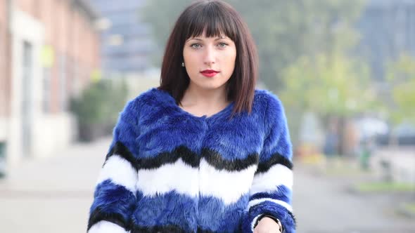 Portrait of young beautiful eastern woman posing outdoor in the city, looking over, serious