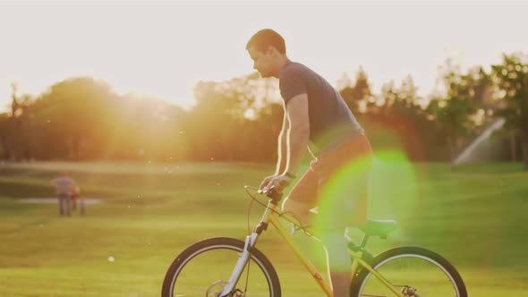 Cyclist Rides on the Lawn at Sunset