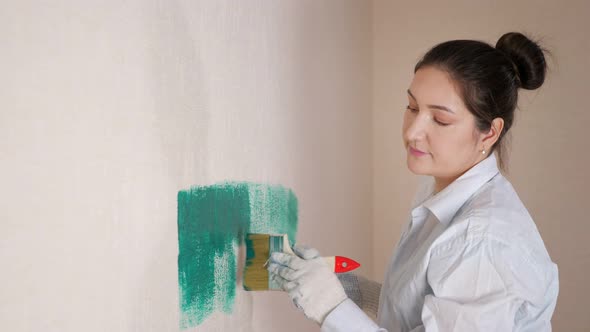 Brunette in White Shirt and Gloves Paints Wall in Turquoise