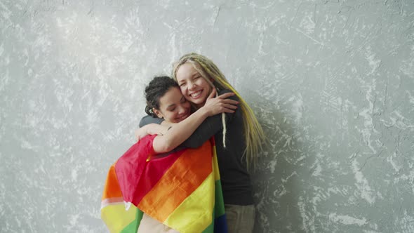 Covered with LGBTQ Flag Girl Tenderly Hugs Her Girlfriend