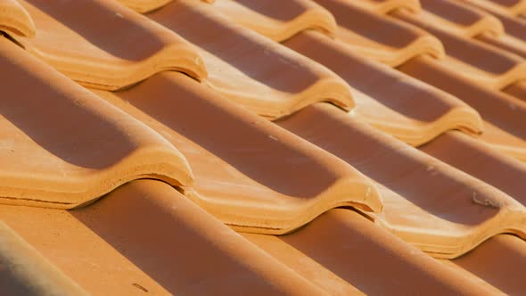 Overlapping rows of yellow ceramic roofing tiles covering residential building roof.