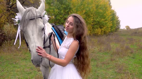 Bride in White Dress Feeding and Stroking Horse. Close Up