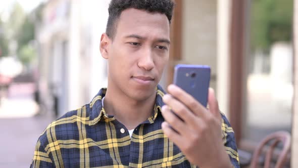 Young African Man Upset By Loss on Smartphone