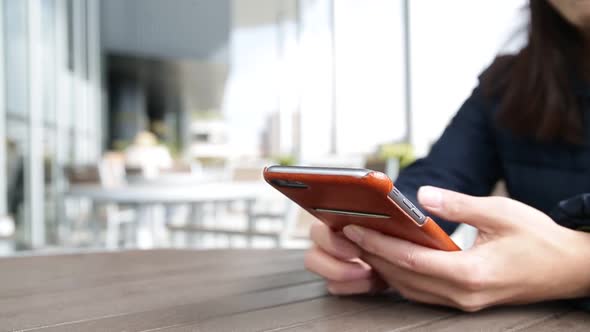 Woman typing on mobile phone at coffee shop