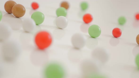 Many colorful bonbons on white reflective background randomly positioned 4K 2160p 30fps UltraHD vide