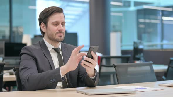 Businessman Browsing Internet on Smartphone in Office