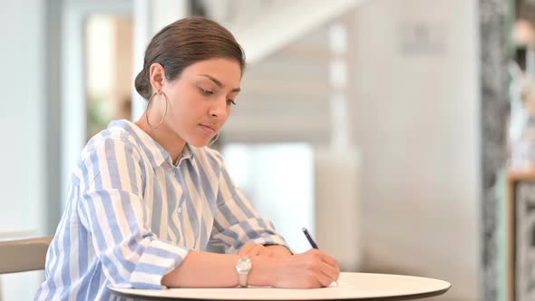 Young Indian Woman Doing Paperwork in Cafe 