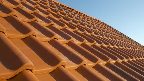 Overlapping Rows of Yellow Ceramic Roofing Tiles Covering Residential Building Roof