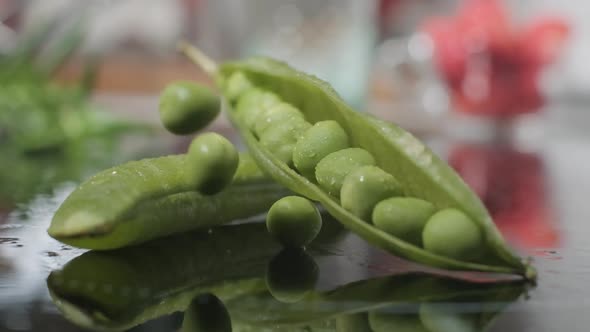 Green Pea Seeds Falling Into Wet And Open Pod Of Green Peas. - close up, slow motion