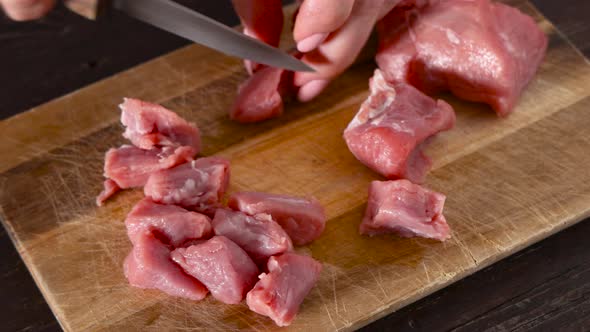 Woman hands cut a piece of raw veal meat into slices with a metal knife
