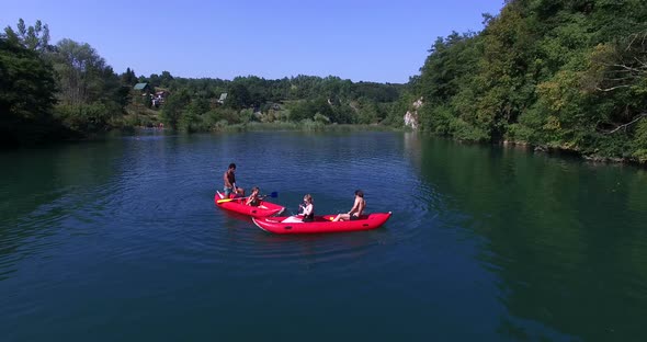 Four young friends paddling canoe and splashing each other with water