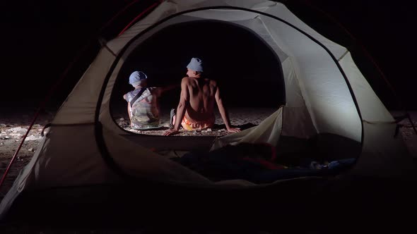 Son and Father Near the Tent at Night