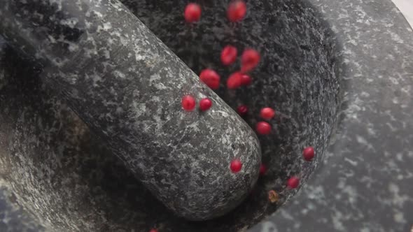 Rose-red Peppercorns Are Falling Into the Grey Stone Mortar