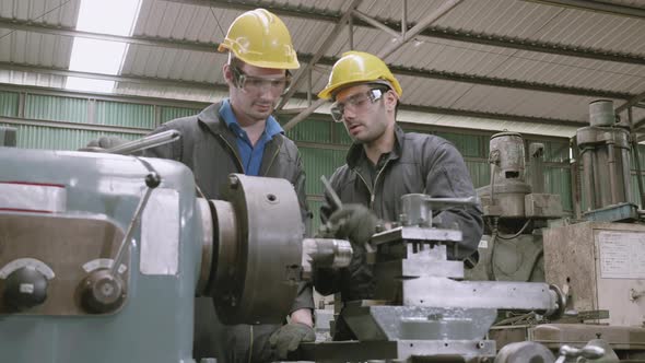 Engineer man training with foreman for apprentice using lathe, apprenticeship teaching with worker.
