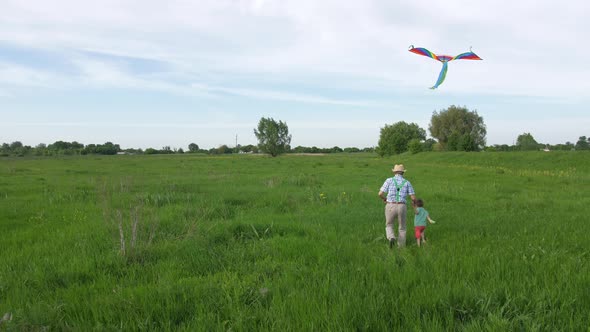 Happy Grandpa and Grandson Running with Kite