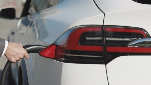 Unrecognizable Man Plugging in Electric Car at Electroic Car Charging Station