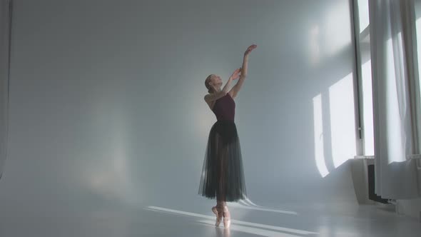 Ballerina in Black Ballet Tutu Dress Dancing Classical Pas in Class Near the Window, Alone Warming