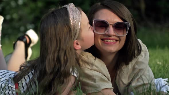 Summer Portrait of Mom and Preschool Daughter Lying on the Grass in the Park