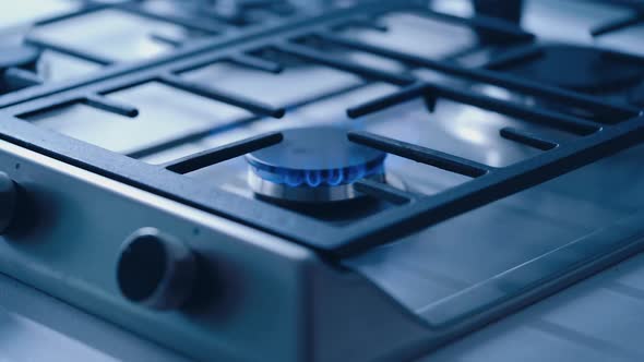 Gas Stove In The Kitchen. Burning blue flames of gas on cook top under grills in kitchen