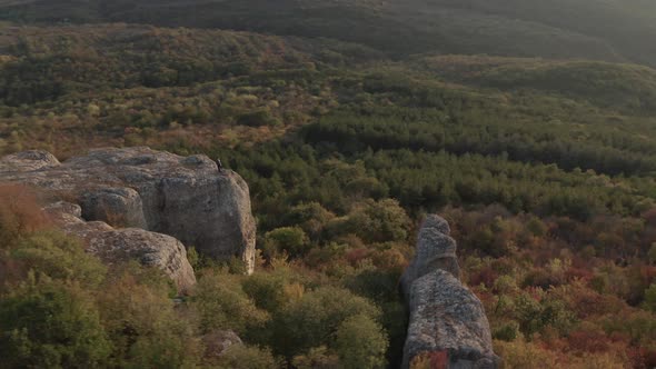 A female hiker with raised hands up at the edge of rock